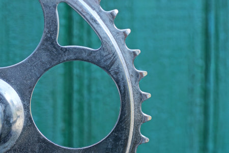 Close up of a gear wheel against the background of green wooden wall