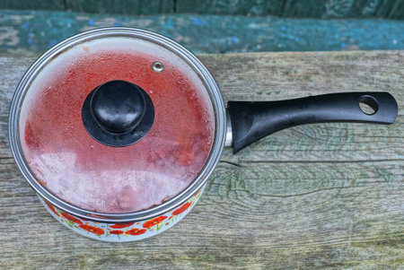Strawberry jam in a saucepan on a wooden table.の写真素材