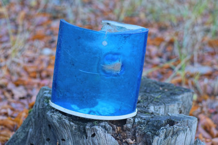 one broken old dirty blue plastic bucket with a hole in the cracks stands on a gray wooden stump in...