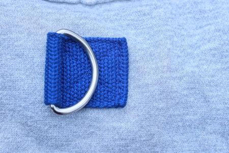 one white metal carabiner rings with blue straps on the gray fabricの写真素材