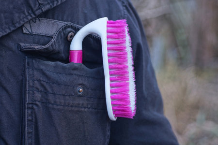 one colored plastic brush lies in the pocket of a black jacket on a man on an autumn streetの写真素材