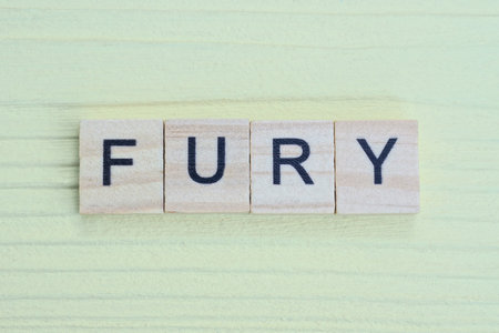 the gray word fury of gray small wooden letters lie on a yellow tableの写真素材