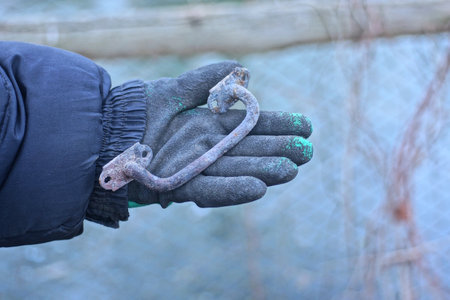 one old gray iron door handle lies on a hand in a glove on an autumn streetの写真素材