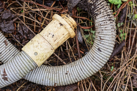 one old dirty gray plastic hose lies on the ground on the streetの写真素材
