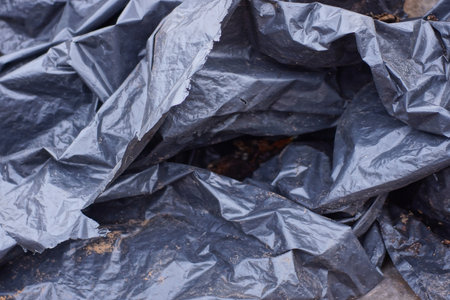 Plastic texture of a piece of crumpled black cellophane in the streetの写真素材