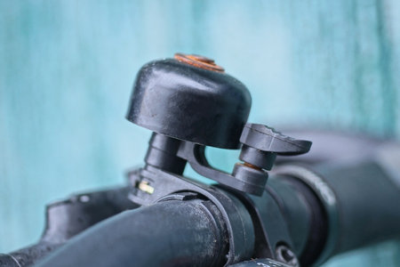 one black bicycle bell on the metal handlebar of a sports bike on the street on a green background