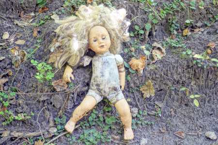one gray brown dirty torn old doll toy lies on the groundの写真素材