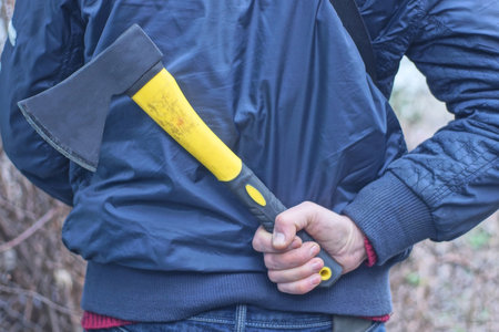 one man in blue clothes hides his hand with a yellow black ax behind his back