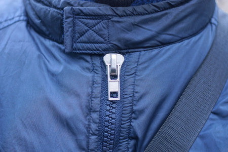 one white closed metallic zip on blue synthetic clothing fabric in the street