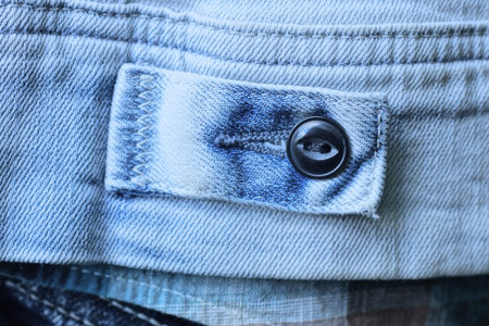 one black plastic button on a pocket made of blue fabric on clothes