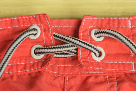 part of red fabric sweatpants with elastic and white black long laces on the table
