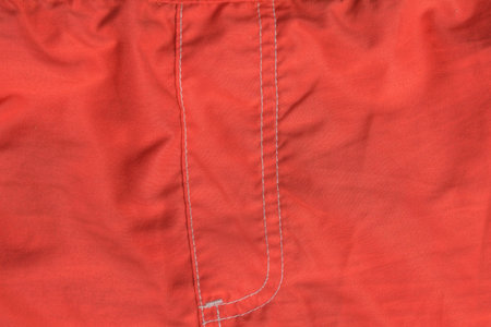 texture of a fabric made of red crumpled matter with a white edging seam on clothesの写真素材