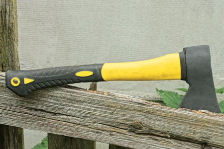 one big black yellow ax lies on the gray board of an old fence on a rural streetの写真素材