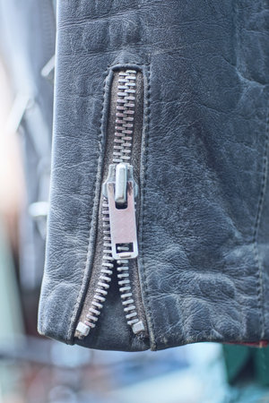 one black leather sleeve of an old jacket with a gray metal zip on a spring street
