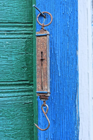 one old long brown iron scale in rust hanging on green blue wooden wall outsideの写真素材