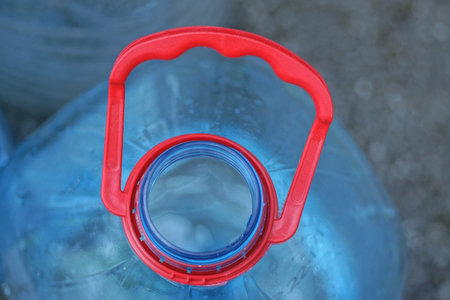 part of one old open empty blue plastic bottle with a red handleの写真素材