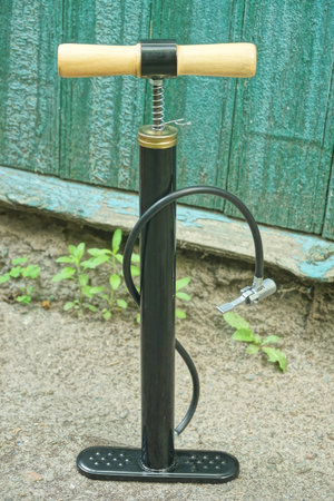 one black pump with hose stands on the gray asphalt near the green wall
