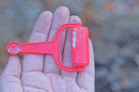 one small red plastic roller toy lies on the palm of the hand on the summer streetの写真素材