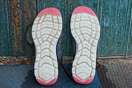 two sneakers with white pink soles stand on a blue floor near a green wallの写真素材