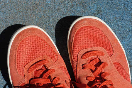 two red sports sneakers made of fabric and suede stand on the blue floorの写真素材