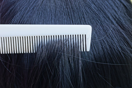one white plastic comb combs black long hair on headの写真素材