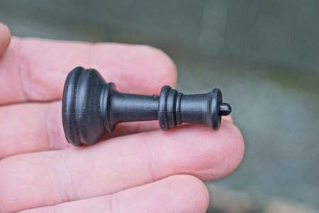one black chess piece king lies on fingers palm on hand on gray background