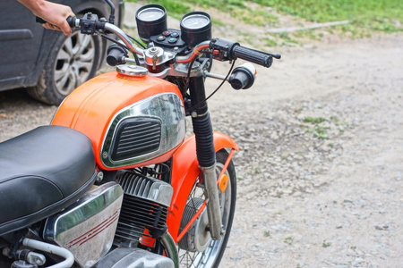 a mans hand holding the handlebars of an old motorcycle on a city street