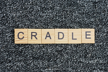 text the word cradle from wooden small letters with black font on an gray tableの写真素材