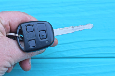 hand holds a one gray iron electronic car key with a black plastic handle on a blue backgroundの写真素材