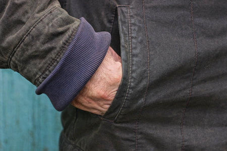 part of black winter jacket with hand in pocket on one man on winter street