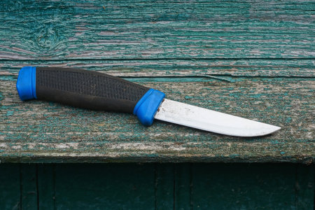 one knife with a black blue plastic handle lies on a green wooden tableの写真素材