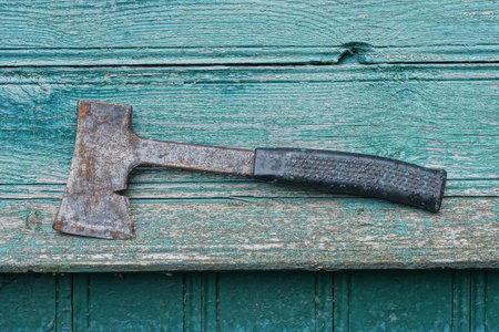 one big black gray ax lies on a green wooden table