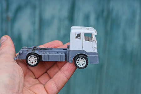 hand holding one small plastic white gray toy car truck on green wall backgroundの写真素材