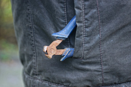 one brown rusty old iron pliers nippers lies in a gray jacket pocketの写真素材