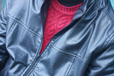 one man in wool red sweater under black leather jacket on autumn streetの写真素材