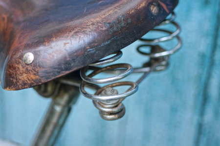 one old gray iron spring on a bicycle brown saddle on a backgroundの写真素材
