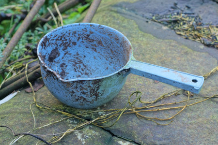 one empty dirty blue plastic ladle stands on an iron brown rusty table on an autumn streetの写真素材