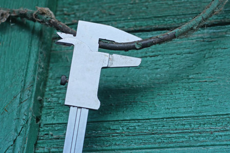 One gray metal caliper measures the diameter of a black wireの写真素材