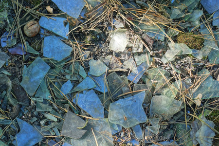 texture from a pile of white glass pieces of broken bottles on gray sand on the street
