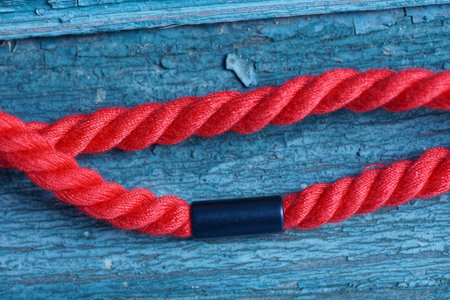 A red cord rope with a black clip lies on a green surface