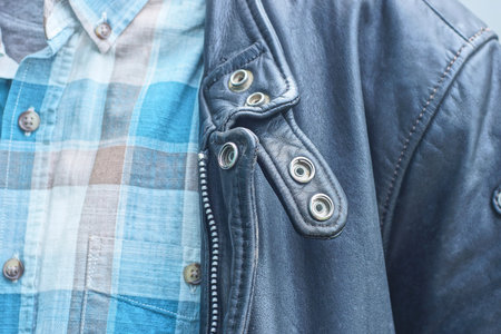 one man in a black leather jacket and a colorful shirt on the street during the day