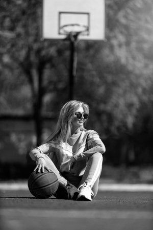 sports girl blonde sits on the basketball court black and whiteの写真素材