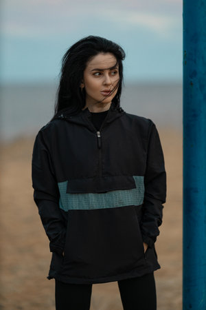 Fitness girl on outdoor sports ground in an anorak in windy weather