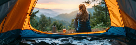 woman sits peacefully in a tent, gazing out at breathtaking mountains in the distance, surrounded by natures beauty.の素材