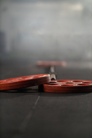 Weights lie on a gym floor after a strenuous workout session showcasing a barbell ready for the next lift in a well lit fitness center. The atmosphere reflects intensity and determination.の写真素材