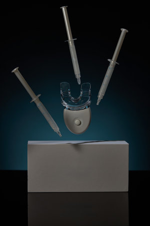 Teeth whitening kit features a clear mouth tray with three syringes ready for use. Product is placed...