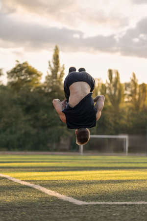 man executes an impressive backflip on a football field enjoying the moment with headphones in his...