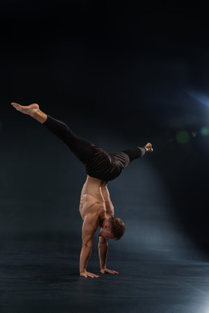 muscular man balances on one hand while performing a handstand showcasing strength and balance. The...