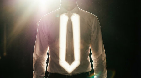 A man wearing a tie stands confidently under bright lights in an indoor setting. The light creates a striking effect on his attire. The atmosphere shows a formal event taking place at night.の素材