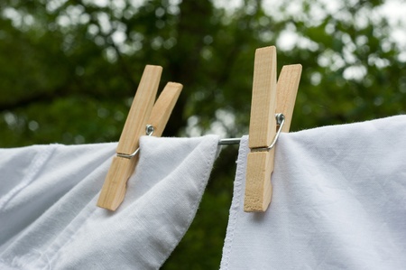 Clothes drying in the wind hanging on a clothesline held by pegsの写真素材